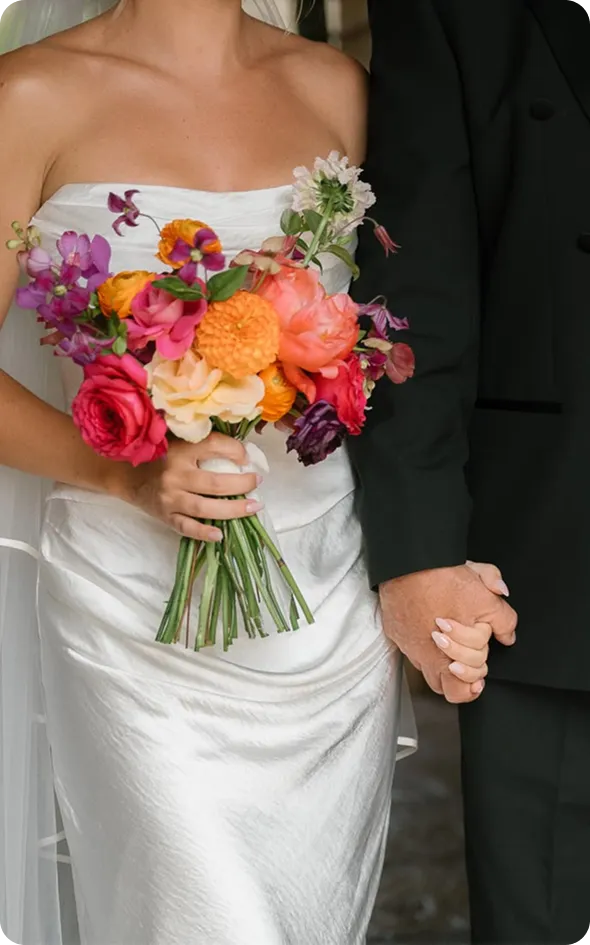 Sposa con bouquet colorato mano nella mano con lo sposo